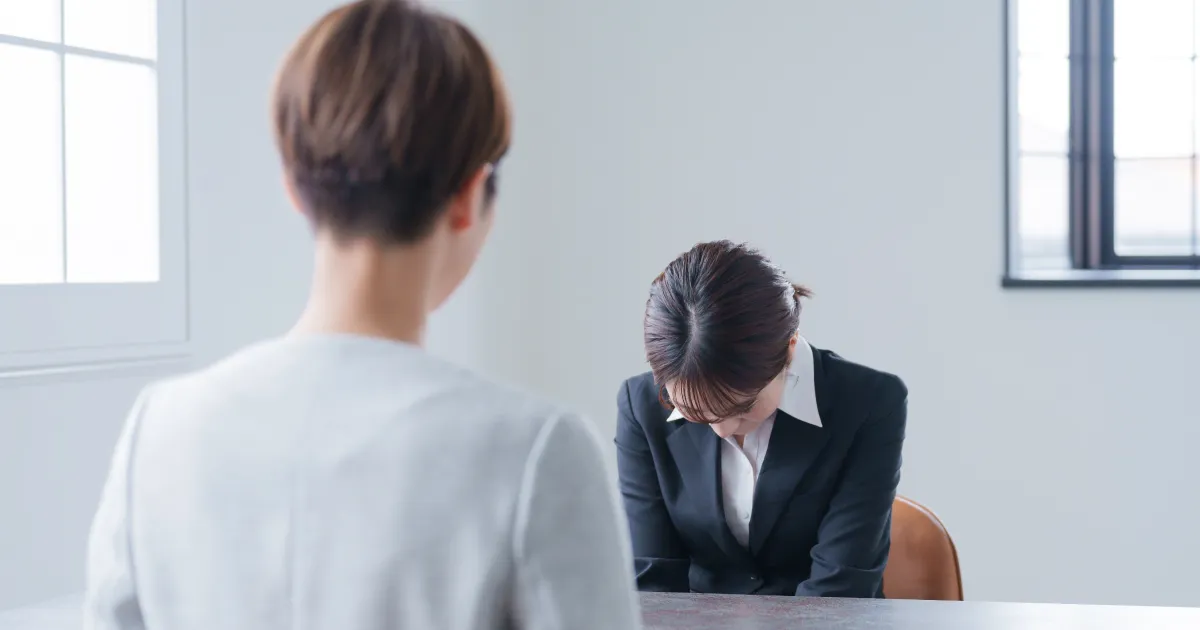 退職理由を説明し、上司に頭を下げているスーツ姿の女性。円満退職をスムーズに進める退職理由の伝え方を説明するシーンのイメージ。