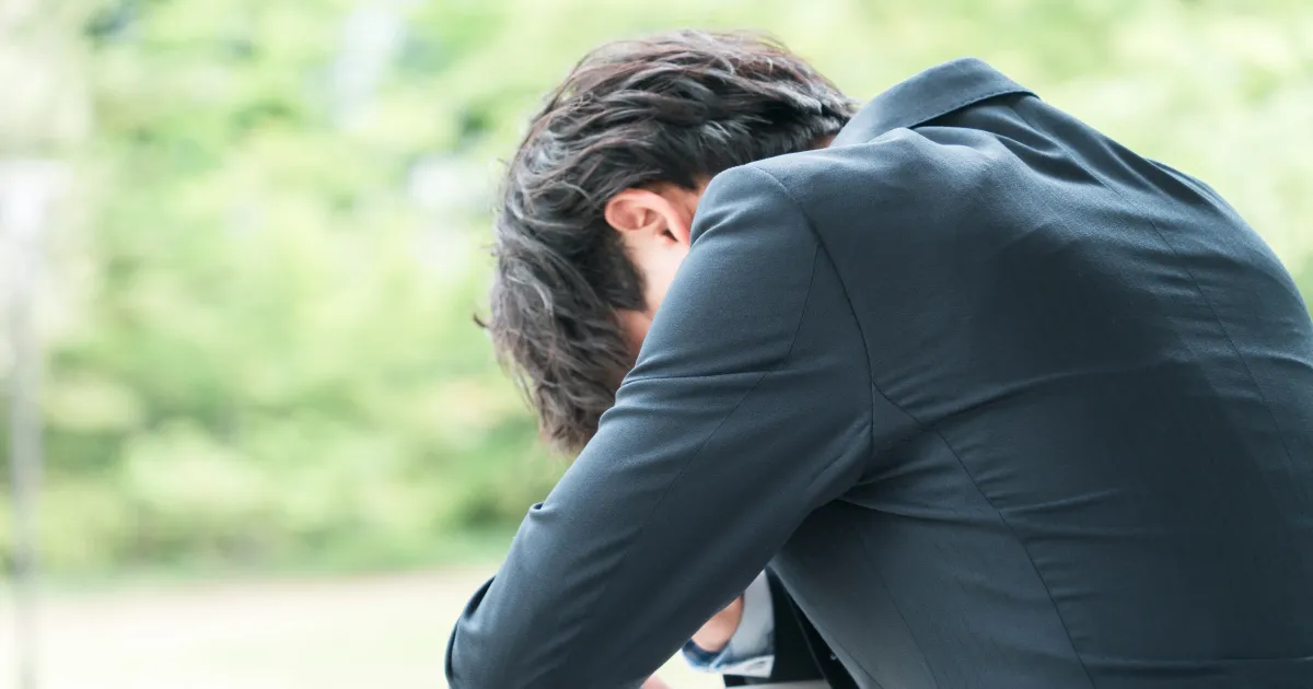 頭を抱えて悩むスーツ姿の男性。円満退職に失敗した場合のよくあるトラブルとその回避方法を説明するセクションのイメージ。