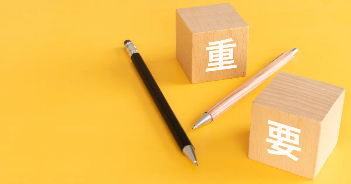 黄色い背景に置かれた『重要』と書かれた木製ブロックとペン。履歴書写真の重要性を象徴するイメージ画像。