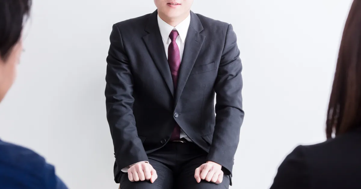 面接中にスーツ姿で座り、緊張感を持ちながら受け答えをしている男性の様子。面接の受け答えで意識すべきポイントについて説明するセクション用の画像。