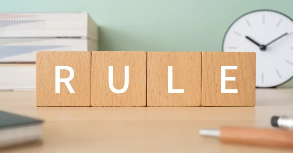 デスク上に置かれた『RULE』と書かれた木製ブロック。履歴書写真のルールに関するセクションを象徴するイメージ画像。