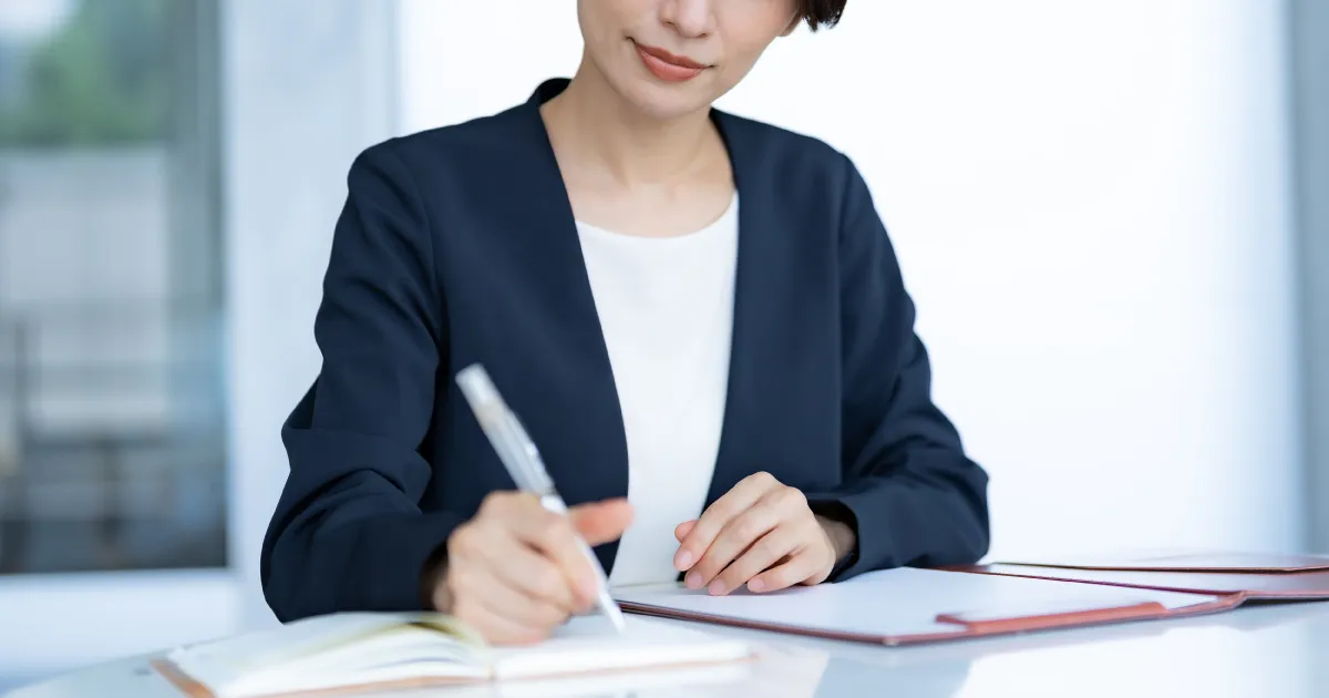 面接中にメモを取るスーツ姿の人物の手元。転職面接で採用担当者の心をつかむフェーズ別逆質問の重要性を説明するセクションを象徴する画像。