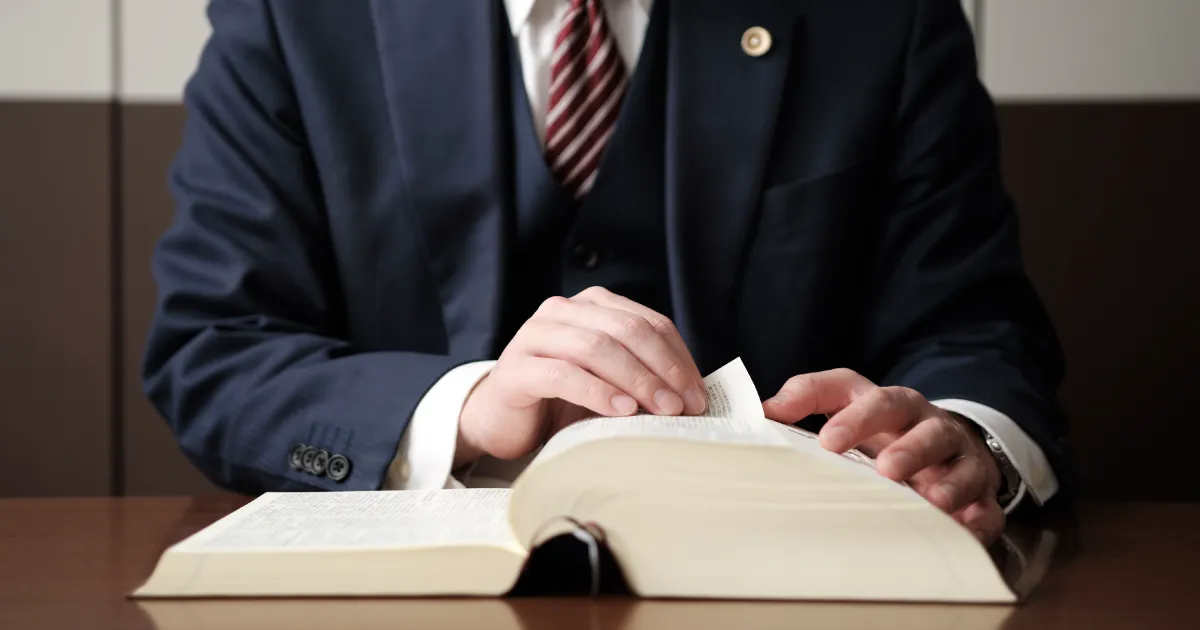 法律書をめくるスーツ姿の男性。退職時の引き止めに関する法律を調べているイメージ。