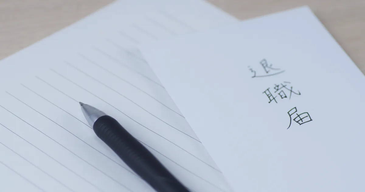 退職届の書類とペンが机に置かれている。退職届の作成を示すイメージ。