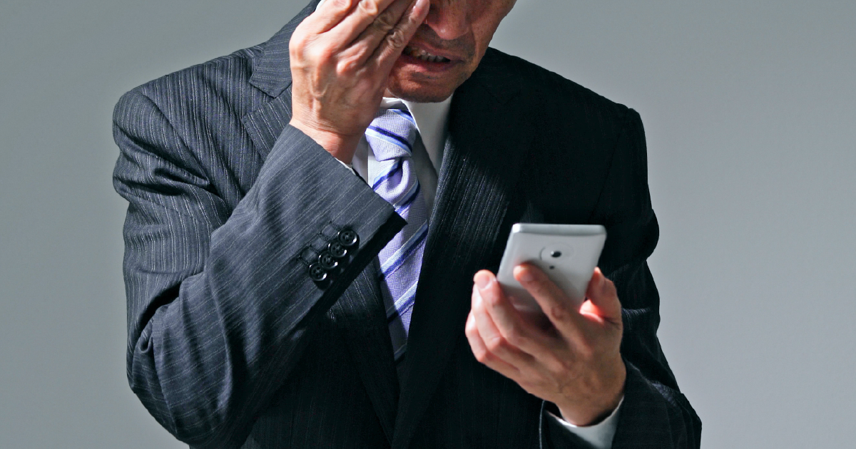 スマートフォンを手にしながら悩む表情のシニア男性 - シニア層の転職が難しい理由を説明するセクションのイメージ