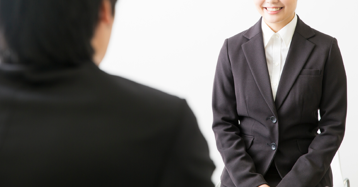 退室前に笑顔で面接官に向き合うスーツ姿の女性 - 面接終了時の正しい退室マナーを示すイメージ