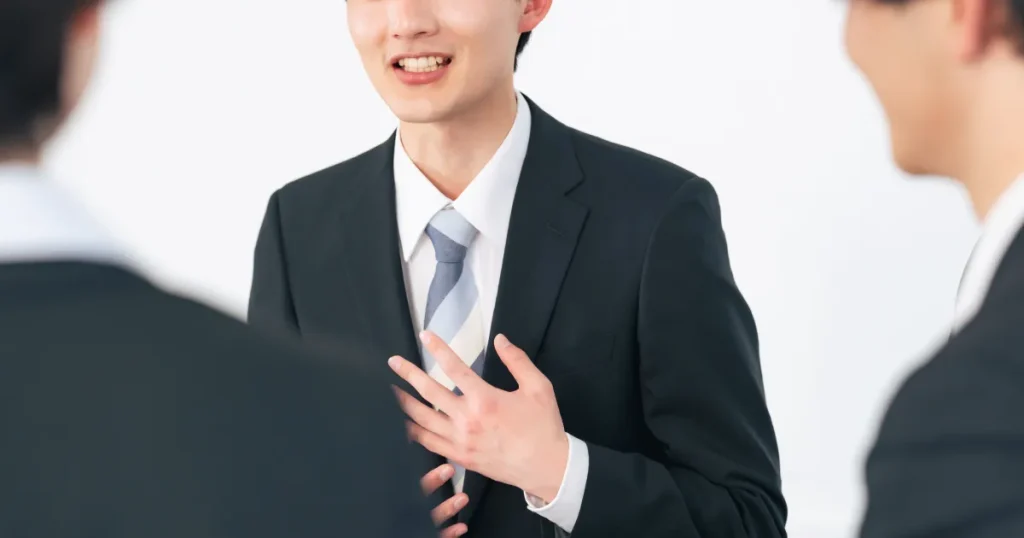 スーツ姿の男女が対話をしている様子。他己分析の手法について説明する場面をイメージした写真。