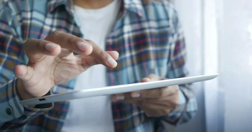タブレットを操作するチェック柄のシャツを着た人 - フリーターから転職するための具体的なコツを説明するセクション