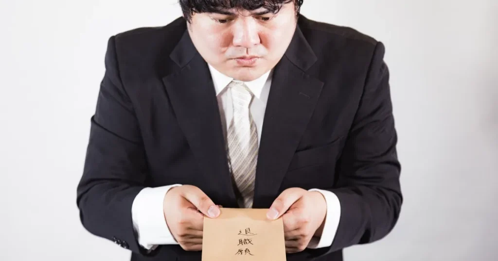 退職願を差し出すスーツ姿の男性 - 退職代行サービスのデメリットを説明するセクションに関連した画像