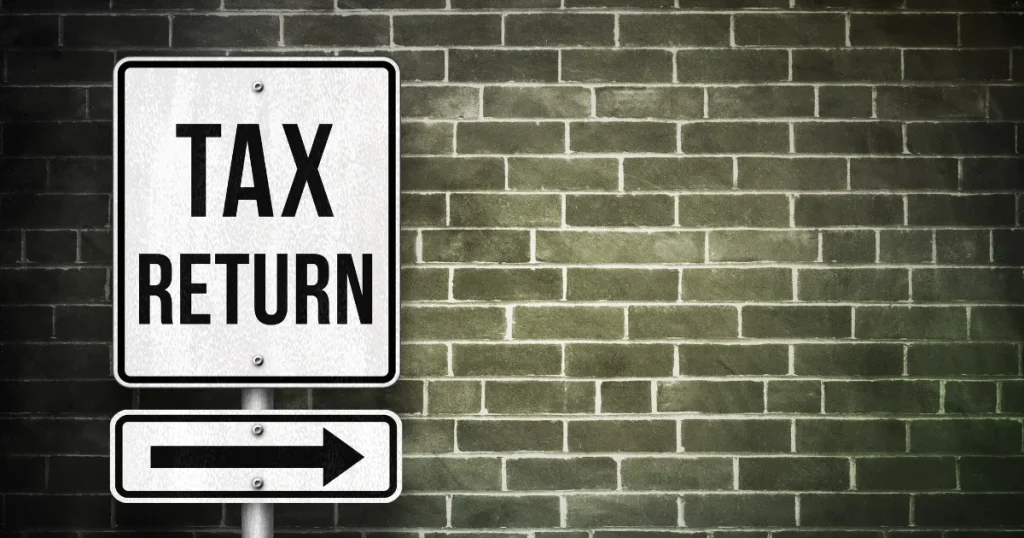 TAX RETURN（確定申告）の標識と矢印が描かれた看板。転職後の確定申告で注意すべきポイントを示唆するイメージ。