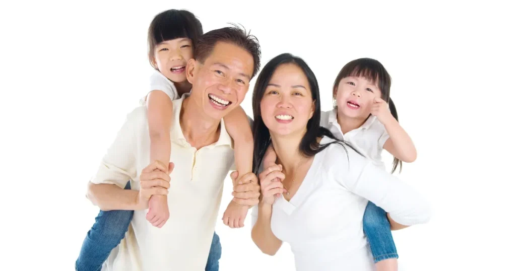 顔でポーズをとる4人家族の写真。父親と母親がそれぞれ子どもを背中に乗せた楽しそうな様子を表現。