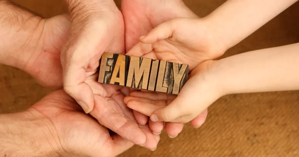 大小の手が重なり合い、その中に『FAMILY』と書かれた木製ブロックが置かれている様子。家族の絆とプライバシーを象徴するイメージ。