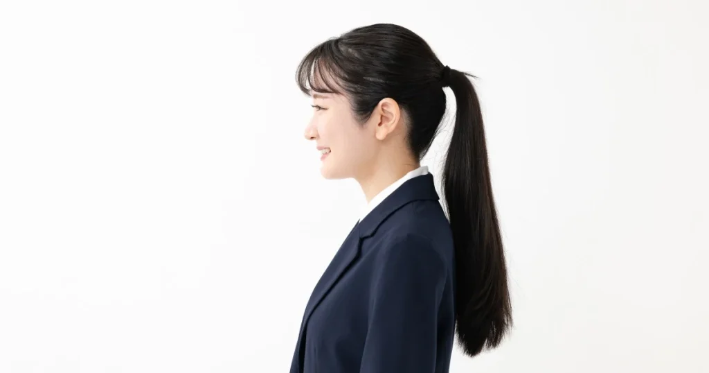 面接に適した清潔感のあるポニーテールの女性 - 笑顔で横を向くスーツ姿