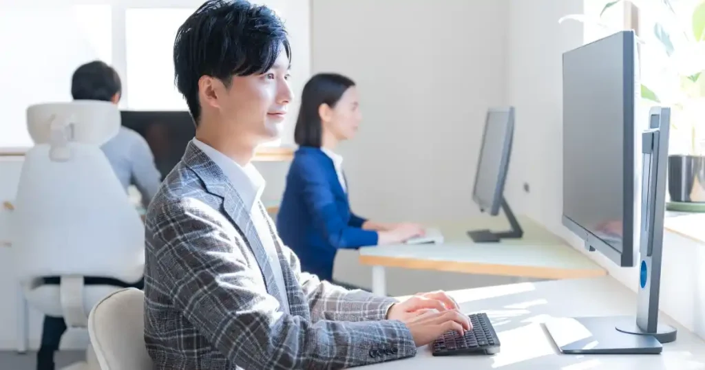オフィスでパソコン作業をするビジネスカジュアルの男性 - フリーターから転職しやすい職種4選を説明するセクション
