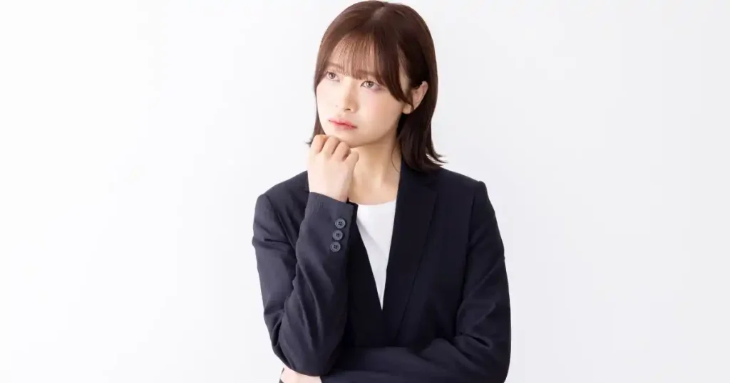 スーツ姿で考え込む女性 - 面接中のトラブル対応方法をイメージした写真