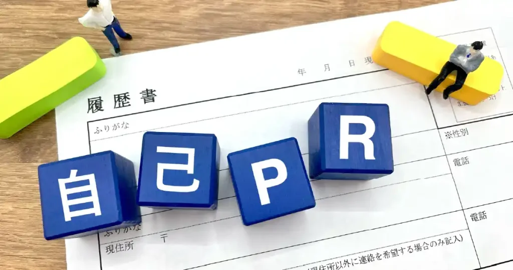 履歴書の上に置かれた『自己PR』と書かれた青いブロックとミニチュアの人形 - 自己PRの重要性について説明するセクションのイメージ