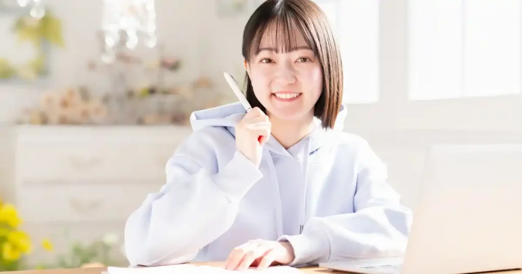 ペンを持ちながら微笑む女性 - 自己分析に役立つフレームワークの説明セクションのイメージ