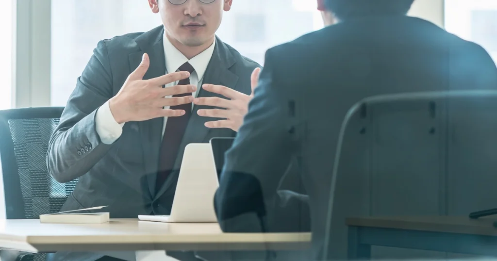 スーツ姿の男性が退職の意志を上司に伝える様子 - Uターン転職での退職手続きに関するポイントを説明する画像