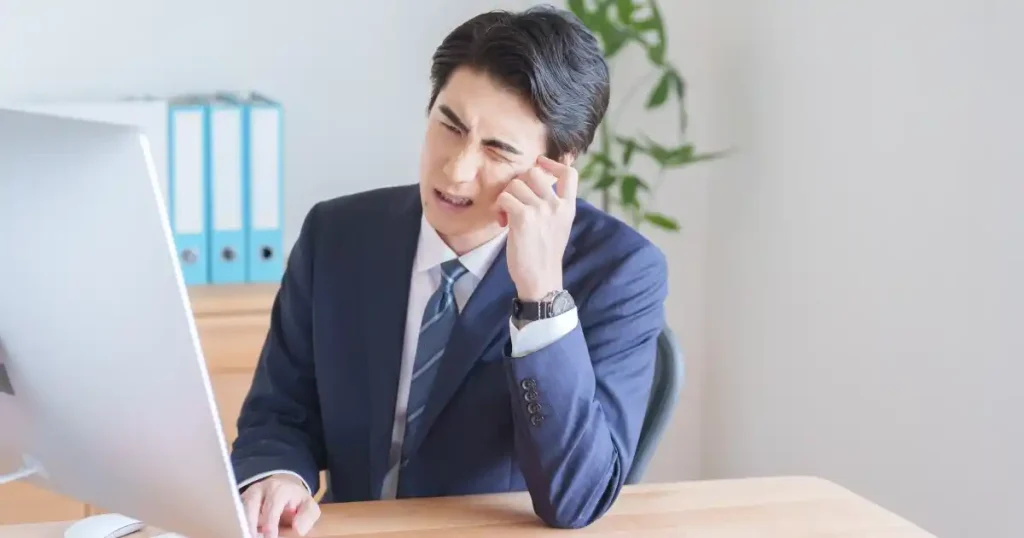 スーツ姿で悩む男性 - 働きながら転職活動をする際によくある失敗を象徴するイメージ