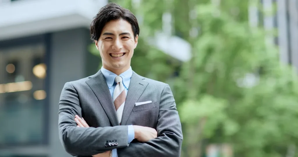 スーツ姿で笑顔の男性 - 新卒が社会人デビューを成功させるための8つの必須スキルを象徴するイメージ