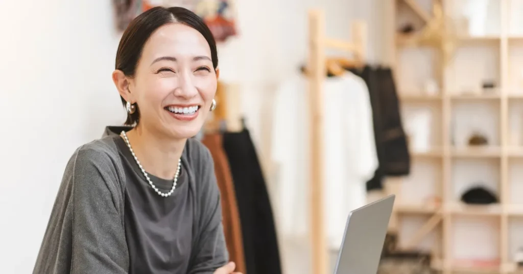 笑顔でノートパソコンを見る女性 - 新卒の社会人デビューの重要性を象徴するイメージ