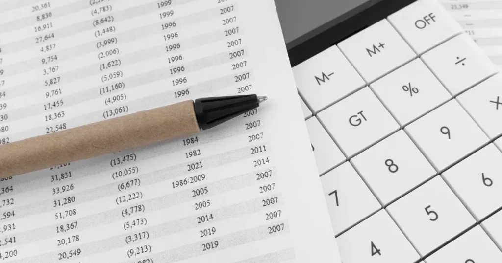 計算用の電卓とデータが記載された書類 - 企業の新卒時年収を調べる方法を説明するセクション用の画像