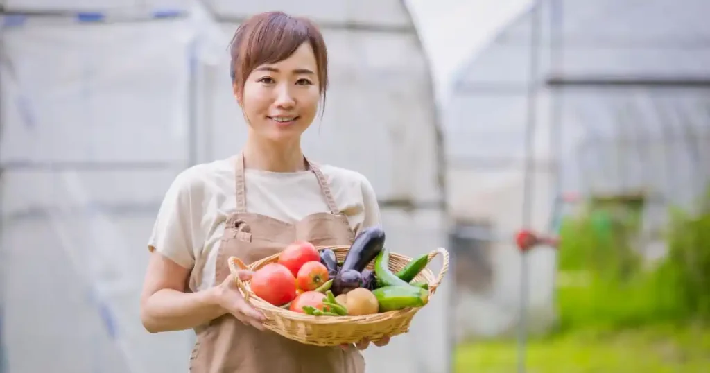 青果バスケットを持つ笑顔の女性スタッフ。青果専門店で働くのに向いている人の特徴を表すイメージ。