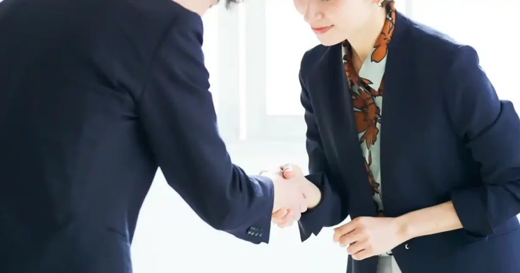スーツ姿の男女が握手を交わしている様子。休職中でも円満に退職するためのポイントを示唆する場面を表現した画像。