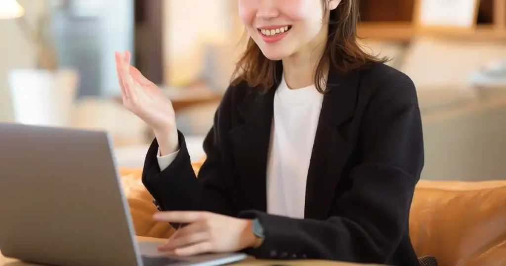 笑顔でノートパソコンの画面に向かいながら話している女性。一人で面接練習するときに意識すべきポイントについて説明するセクションに使用される画像。