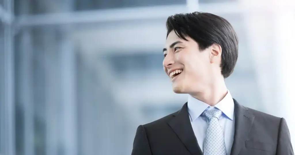 スーツ姿で笑顔を見せる若い男性。転職の可能性と将来性を象徴するイメージ。