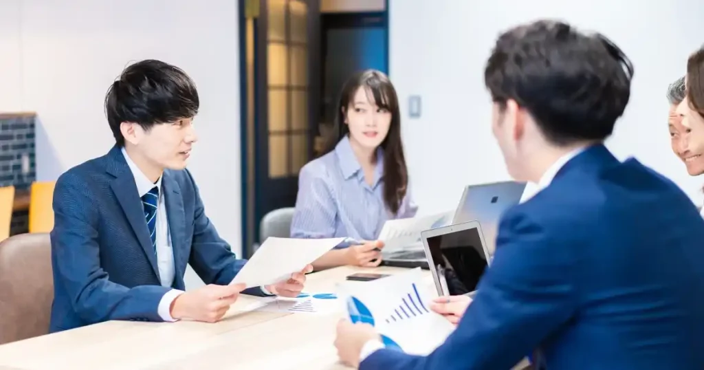 会議室で話し合うスーツ姿の若い男女。転職活動における年齢と経験の違いを象徴するイメージ。