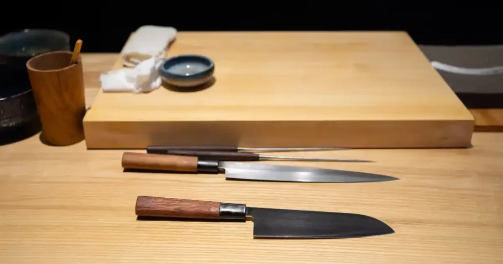 寿司職人の道具が整然と並ぶ作業台。包丁や調理器具が木製のまな板の上に配置されている。