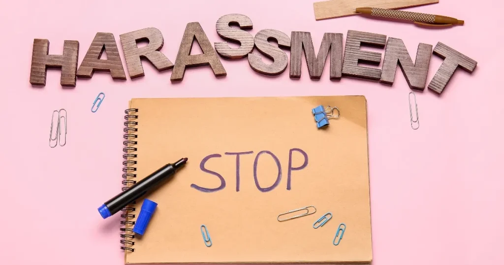 ピンクの背景に置かれたノートに『STOP』と記載され、上部に『HARASSMENT』の文字が並ぶイメージ。オワハラへの対処法について説明するセクションを象徴する画像。