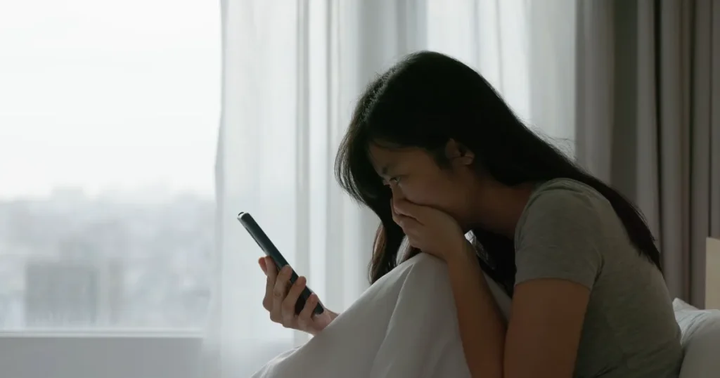 スマートフォンを手にしながら悩む女性。オワハラが発生する原因について説明するセクションを象徴するイメージ。