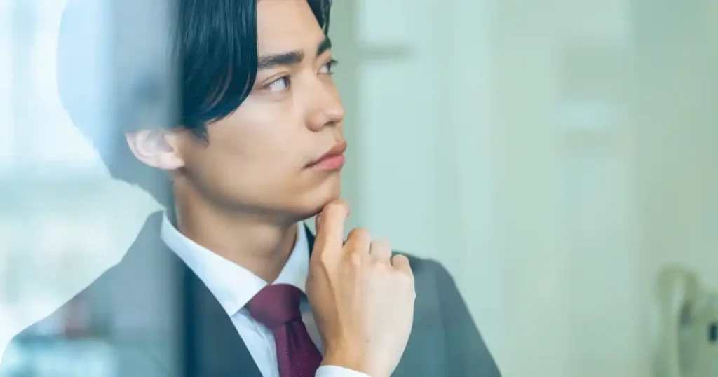 スーツ姿で考え込む男性。就職面接で避けるべき逆質問について説明するセクションのイメージ。