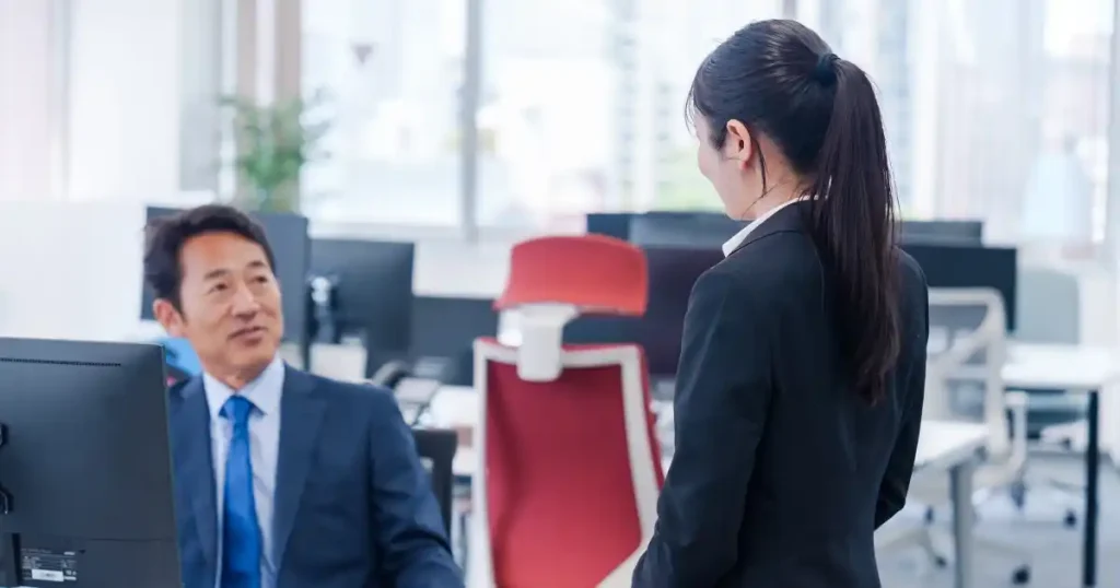 オフィスで上司らしき男性と話をしている女性社員。退職時に有給休暇取得以外でやるべきことについて説明するセクションのイメージ。