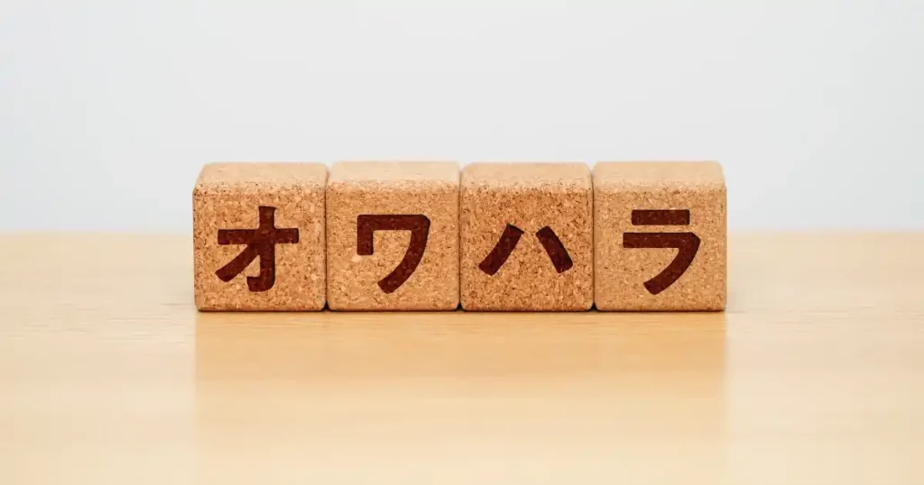 机の上に並んだコルク製のブロックに『オワハラ』と書かれたイメージ。オワハラ（就活終われハラスメント）に関する解説用画像。