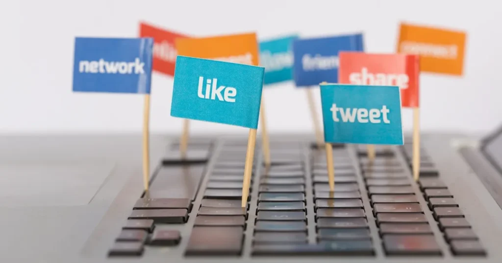 リファラル採用の注意点を表現したイメージ。キーボードの上に『like』『tweet』『share』などの文字が記された旗が立ち、デジタルコミュニケーションを象徴している。