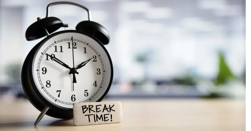 デスクの上に置かれたアナログ時計と『BREAK TIME!』と書かれた小さな看板。退職前に有給休暇を使い切れない主な理由を説明するセクションのイメージ。