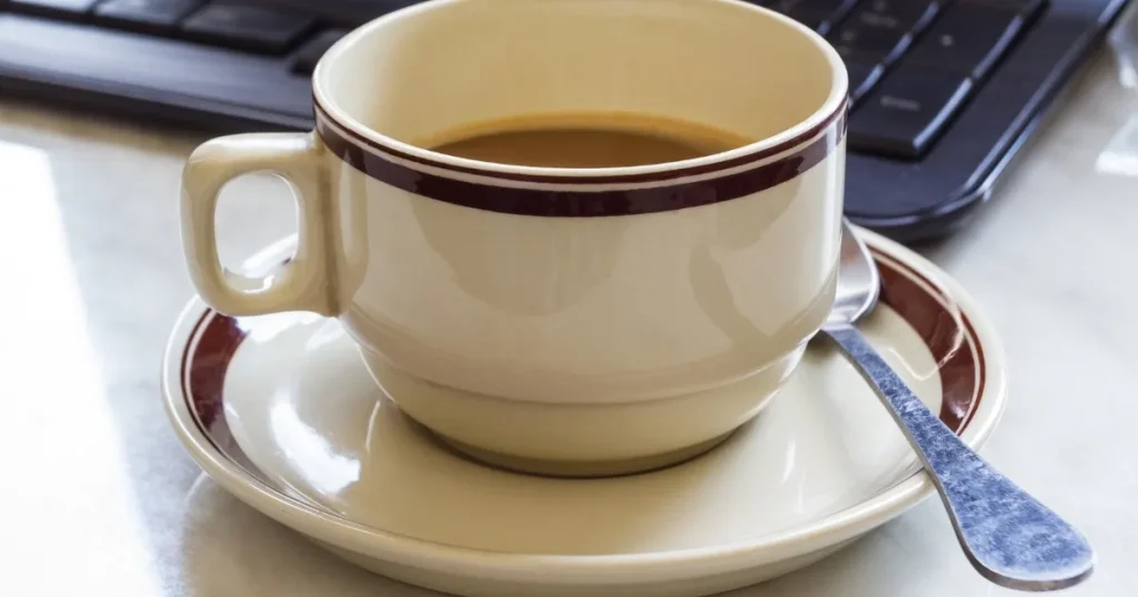 デスクの上に置かれたコーヒーカップとスプーン。背景にはパソコンのキーボードが見える。有給休暇中に次の職場で働くことが可能かについて説明するセクションのイメージ。