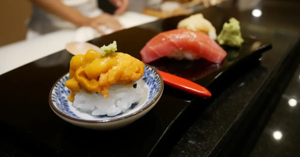 寿司店のカウンターに並ぶ新鮮なウニやマグロの握り寿司。寿司店アルバイトの仕事内容を象徴するイメージ。