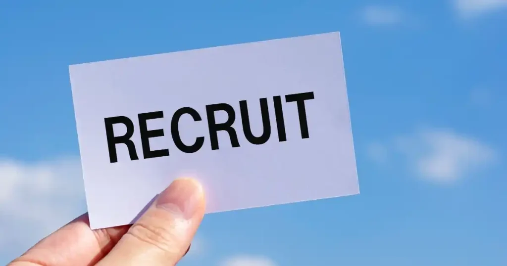 青空を背景に『RECRUIT』と書かれたカードを持つ手。高級寿司店の求人情報を探すための方法を象徴するイメージ。