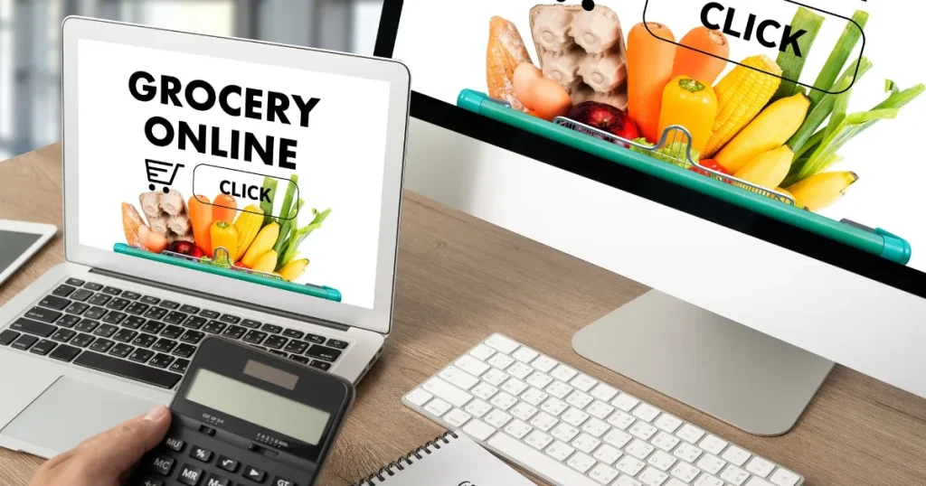 ノートパソコンとデスクトップ画面に「GROCERY ONLINE」の文字と食品画像が表示され、手に電卓を持つ人物の手元が映る。ネットスーパー業務のスキルとしてPC操作や正確な計算が求められることを表現。