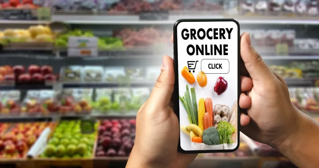 スマートフォンの画面に「GROCERY ONLINE」と表示され、背景にスーパーマーケットの生鮮食品売り場が映っている。ネットスーパーの求人情報やオンラインショッピングの利便性を象徴的に表現。
