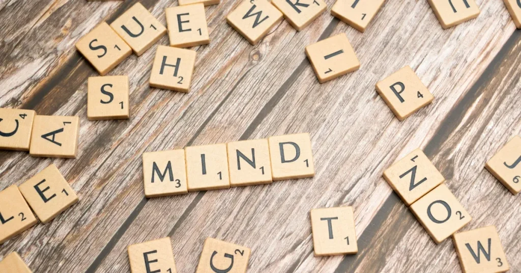 木製のテーブルに散らばる文字ブロックで「MIND」と組まれた単語：志望動機を考える際に役立つツールや思考プロセスを象徴するイメージ。