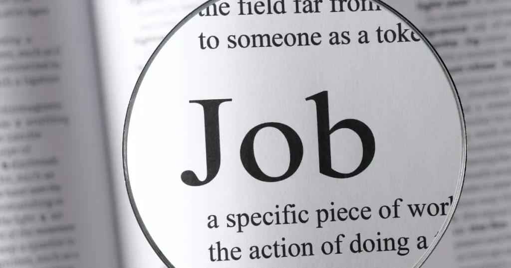辞書のページに「Job」という単語が拡大鏡で強調されている画像。仕事やアルバイトの定義を象徴的に表現している。