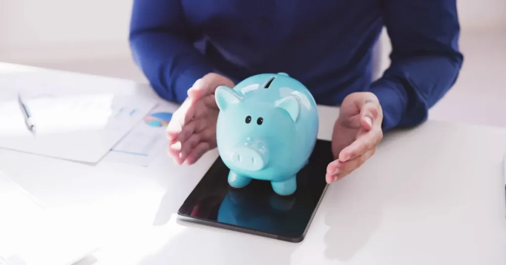 青い貯金箱を両手で囲む人物のイメージ 年収アップを狙いやすい業界を紹介するセクションを象徴する画像
