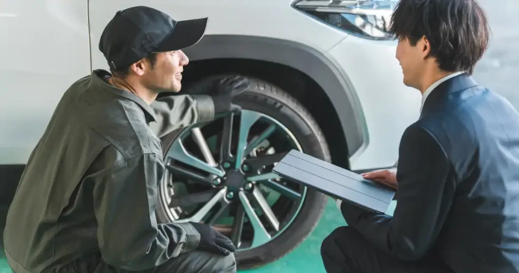 自動車整備士が顧客と対話しながらタイヤの状態を確認している場面｜転職活動における職場選びのポイントを示すセクションで使用