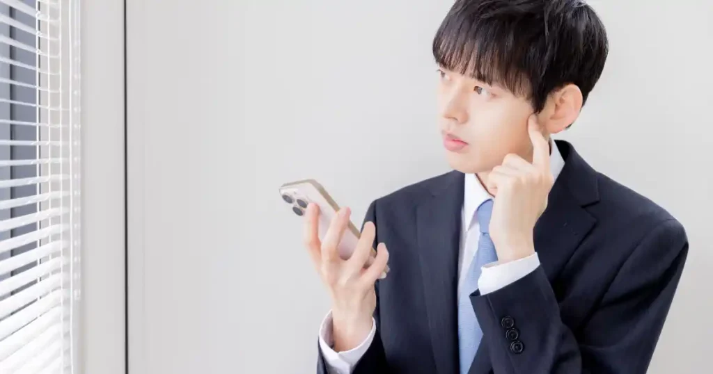 就活中に企業への電話対応について考えるスーツ姿の男性。電話に関するよくある疑問と回答を解説するセクションのイメージ